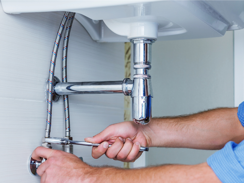 plumber tightening pipes under sink<br />
