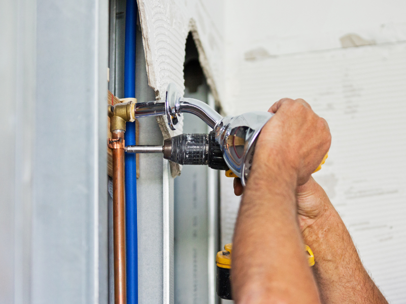 Plumbing emergency -plumber fixing pipes in shower with tiles and wall removed 