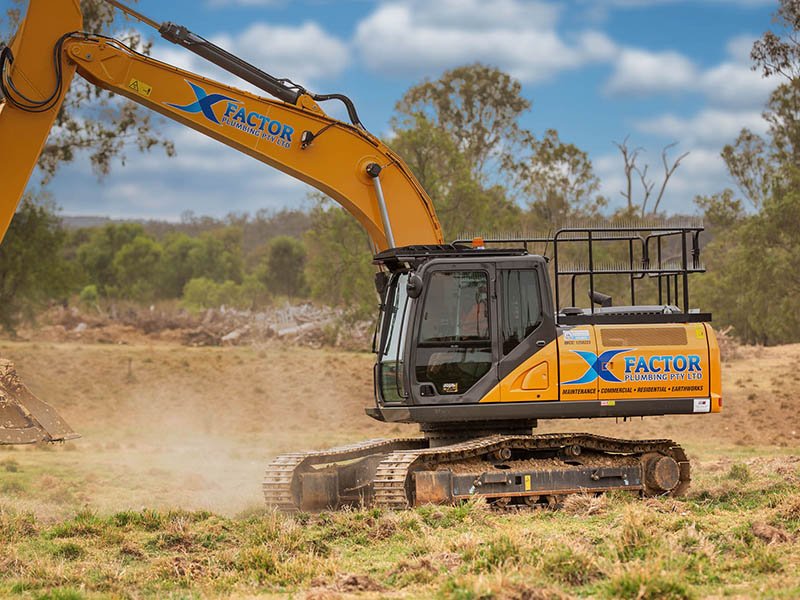 man driving yellow excavator in background digging up from pile of dirt